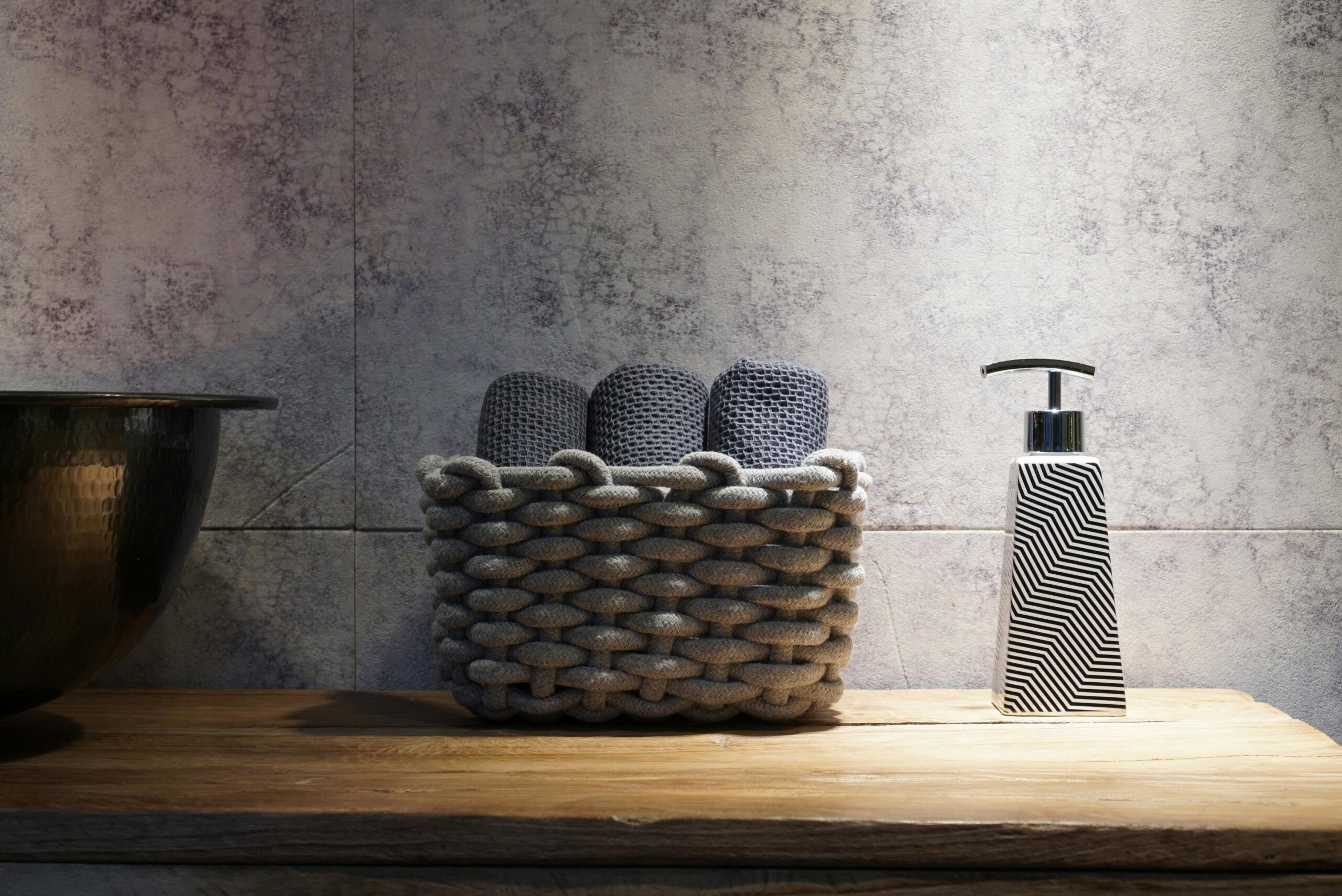 Stylish bathroom setup featuring a woven basket and a contemporary soap dispenser on a wooden countertop.